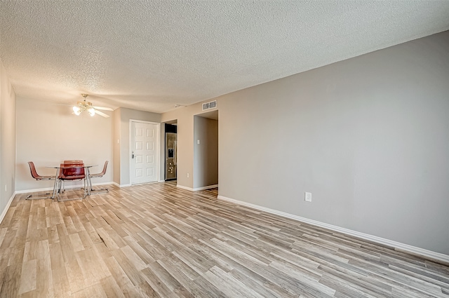 empty room featuring ceiling fan, light wood-type flooring, and a textured ceiling