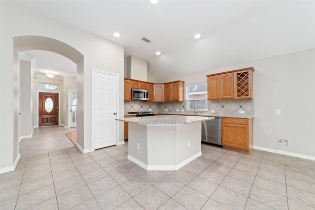 kitchen featuring a center island, stainless steel appliances, a wealth of natural light, and vaulted ceiling