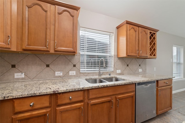 kitchen with decorative backsplash, light stone counters, stainless steel dishwasher, sink, and light tile patterned floors