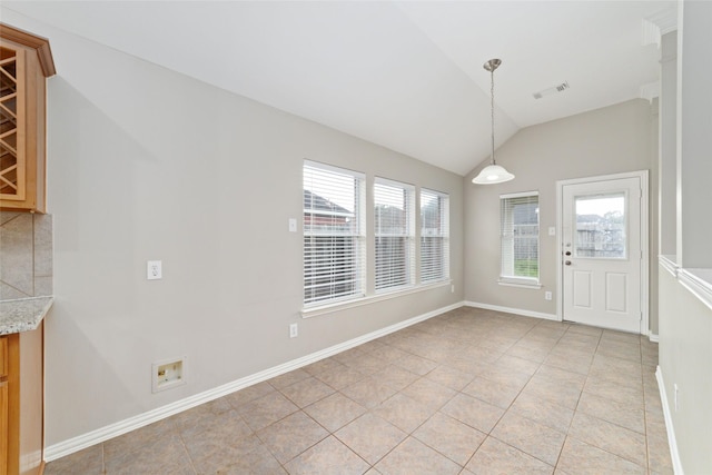 unfurnished dining area featuring vaulted ceiling, plenty of natural light, and light tile patterned flooring