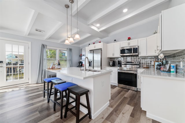 kitchen with white cabinets, dark wood-type flooring, stainless steel appliances, and an island with sink