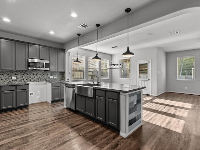 kitchen featuring gray cabinetry, pendant lighting, stainless steel appliances, and a kitchen island with sink