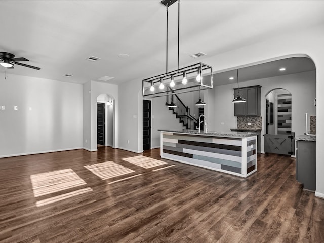 kitchen featuring gray cabinetry, ceiling fan, dark hardwood / wood-style floors, backsplash, and pendant lighting