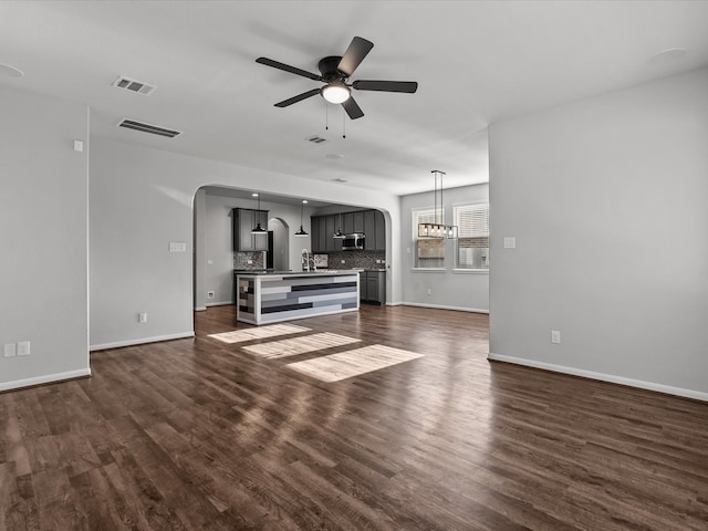 unfurnished living room featuring ceiling fan, sink, and dark wood-type flooring