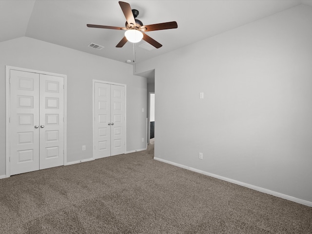 unfurnished bedroom with carpet flooring, vaulted ceiling, ceiling fan, and multiple closets