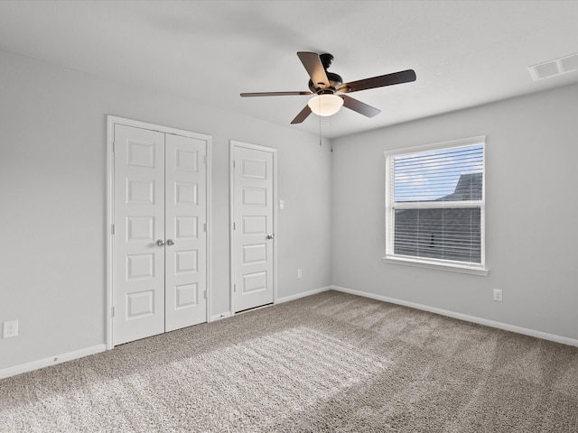 unfurnished bedroom featuring ceiling fan, carpet floors, and two closets