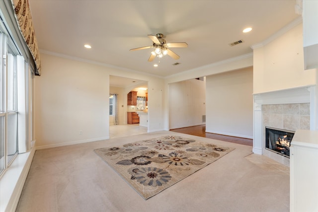 carpeted living room featuring a tiled fireplace, ceiling fan, and ornamental molding