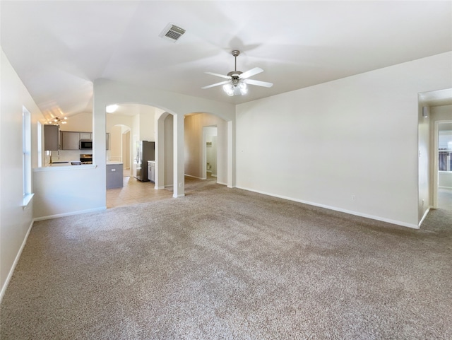 unfurnished living room with light colored carpet, vaulted ceiling, and ceiling fan