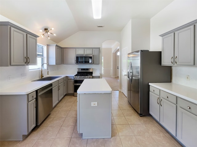 kitchen with appliances with stainless steel finishes, gray cabinets, a kitchen island, and sink