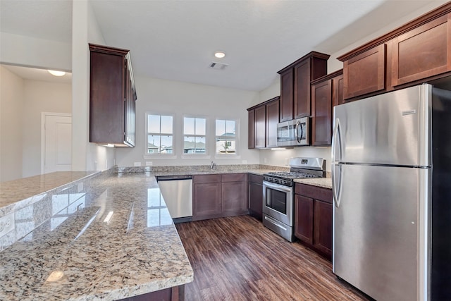 kitchen featuring dark hardwood / wood-style flooring, light stone counters, and appliances with stainless steel finishes