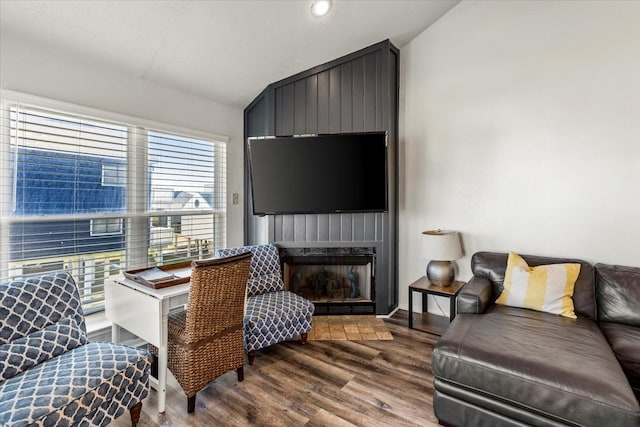 living room with a large fireplace, wood-type flooring, and vaulted ceiling