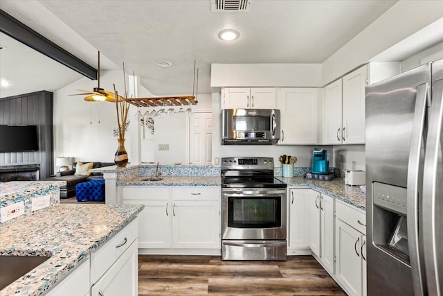 kitchen featuring appliances with stainless steel finishes, dark hardwood / wood-style flooring, ceiling fan, white cabinets, and vaulted ceiling with beams