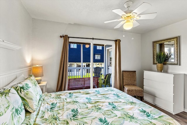 bedroom with access to exterior, ceiling fan, hardwood / wood-style floors, and a textured ceiling