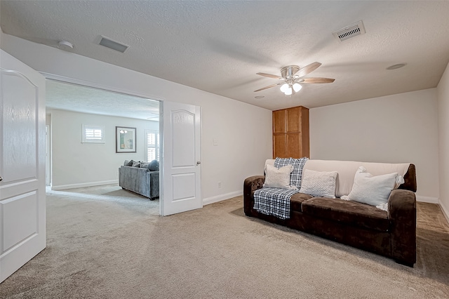 carpeted living room featuring ceiling fan and a textured ceiling