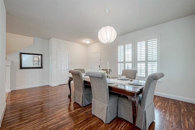 dining space with a textured ceiling and dark hardwood / wood-style flooring