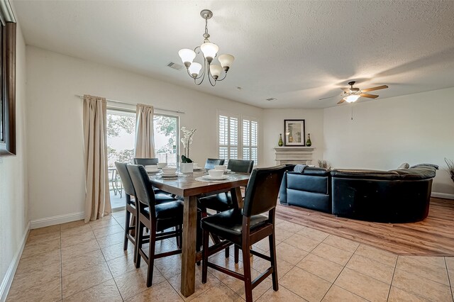 dining space with ceiling fan with notable chandelier, light hardwood / wood-style floors, and a textured ceiling