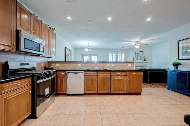 kitchen with sink, stainless steel appliances, decorative backsplash, light tile patterned floors, and ceiling fan with notable chandelier