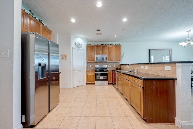 kitchen with pendant lighting, backsplash, sink, appliances with stainless steel finishes, and kitchen peninsula