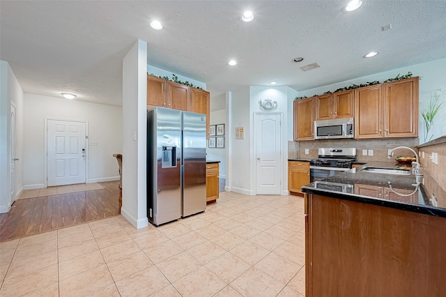 kitchen with sink, decorative backsplash, light tile patterned flooring, kitchen peninsula, and stainless steel appliances