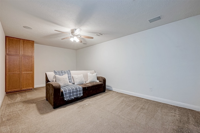 sitting room featuring a textured ceiling, light colored carpet, and ceiling fan