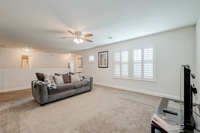 carpeted living room featuring ceiling fan and a textured ceiling