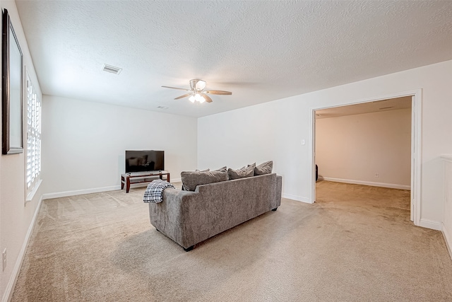 living room with light carpet, ceiling fan, and a textured ceiling