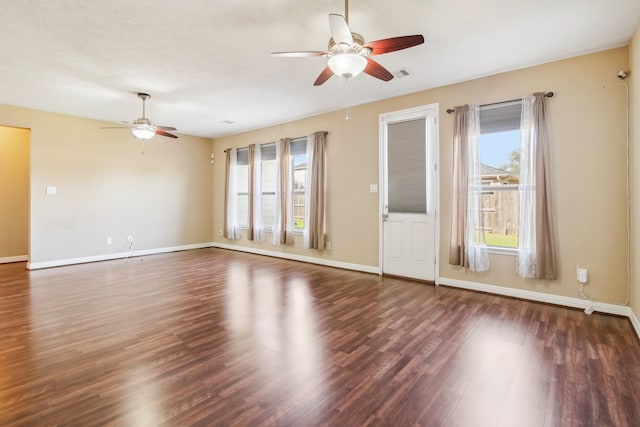 empty room featuring ceiling fan, dark wood-type flooring, and a wealth of natural light