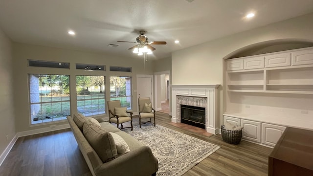 living room featuring dark hardwood / wood-style floors, ceiling fan, and a brick fireplace