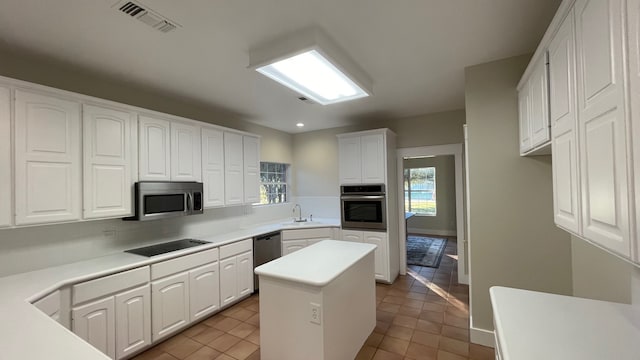 kitchen featuring sink, light tile patterned floors, white cabinets, a kitchen island, and appliances with stainless steel finishes