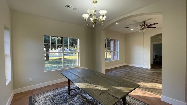 unfurnished dining area with hardwood / wood-style floors and ceiling fan with notable chandelier