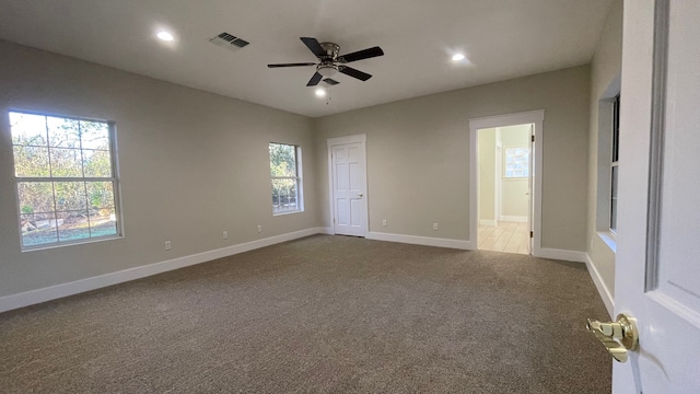 unfurnished bedroom with multiple windows, ceiling fan, carpet, and ensuite bathroom