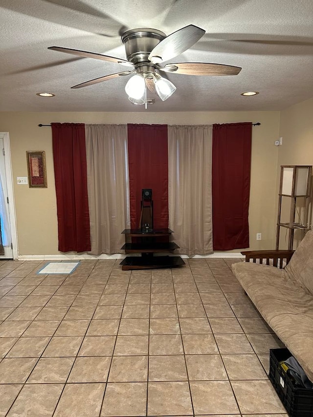 unfurnished living room featuring ceiling fan, light tile patterned floors, and a textured ceiling