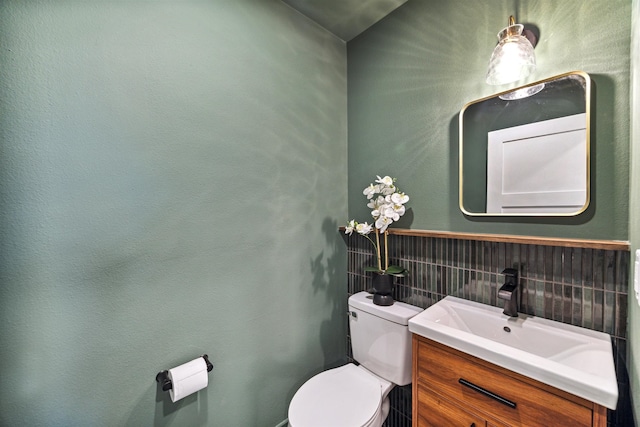 bathroom featuring vanity, toilet, and backsplash