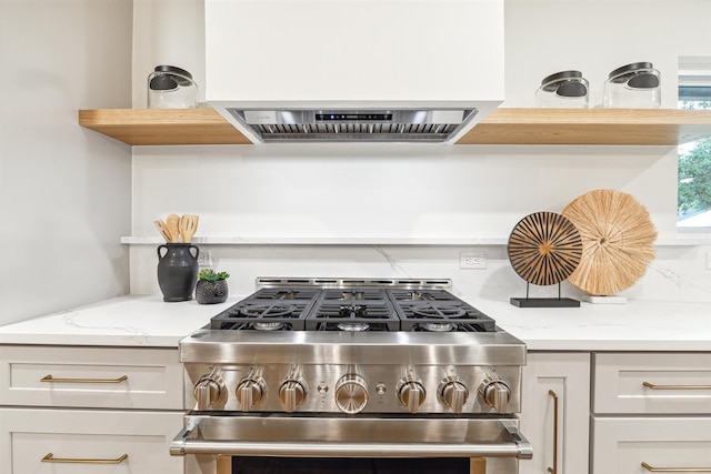 kitchen featuring white cabinetry, light stone counters, stainless steel stove, and extractor fan