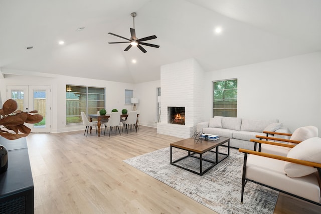 living room featuring a wealth of natural light, a fireplace, ceiling fan, and light wood-type flooring