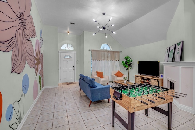 game room with a fireplace, light tile patterned flooring, vaulted ceiling, and an inviting chandelier