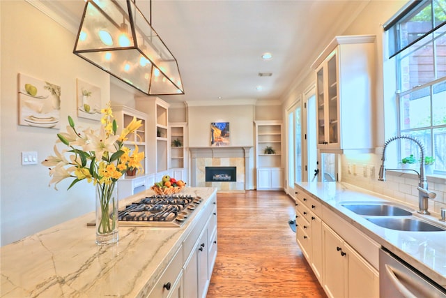 kitchen with white cabinetry, sink, stainless steel appliances, backsplash, and pendant lighting