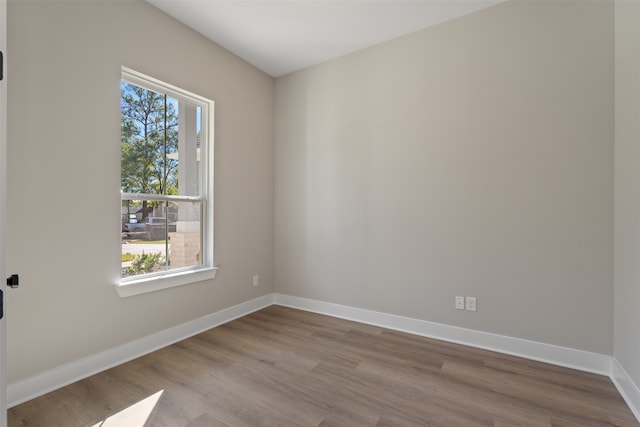 empty room with plenty of natural light, baseboards, and wood finished floors