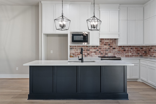 kitchen featuring decorative light fixtures, sink, appliances with stainless steel finishes, and an island with sink