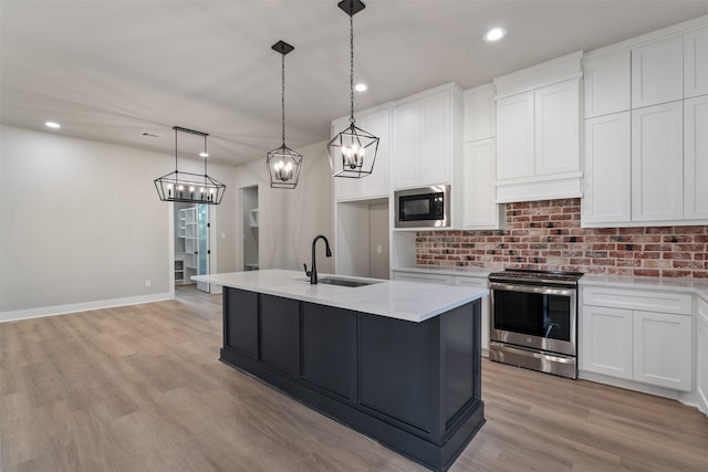 kitchen featuring hanging light fixtures, stainless steel appliances, light hardwood / wood-style flooring, a kitchen island with sink, and white cabinets