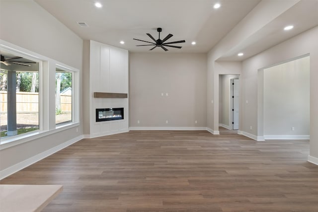 unfurnished living room with a large fireplace, baseboards, a ceiling fan, wood finished floors, and recessed lighting