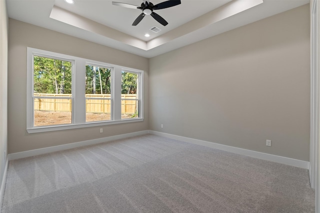 unfurnished room with baseboards, visible vents, a raised ceiling, and carpet flooring