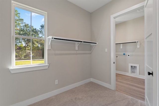 laundry room with electric dryer hookup, hookup for a washing machine, plenty of natural light, and light wood-type flooring