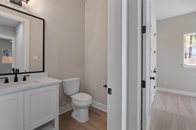 half bathroom with baseboards, vanity, and toilet