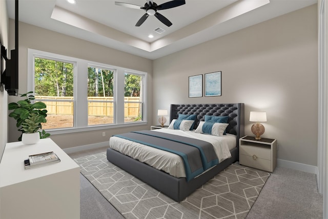 carpeted bedroom featuring visible vents, a tray ceiling, baseboards, and recessed lighting