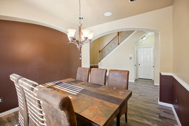 dining area with a notable chandelier, dark wood-type flooring, and vaulted ceiling