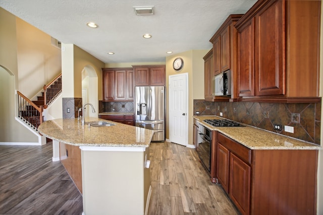 kitchen featuring black appliances, light stone counters, sink, and hardwood / wood-style flooring