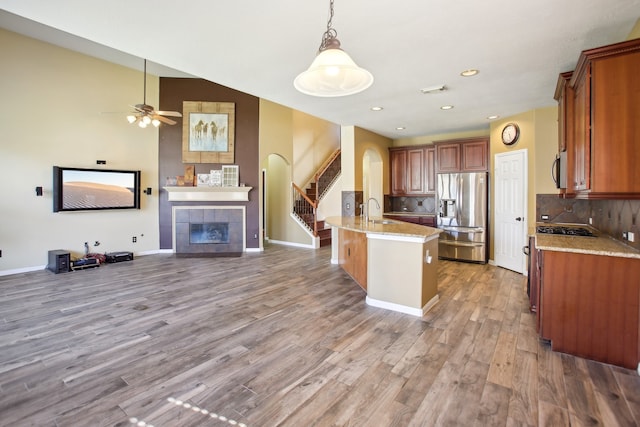 kitchen with sink, light hardwood / wood-style flooring, decorative backsplash, appliances with stainless steel finishes, and a tiled fireplace