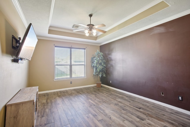 unfurnished room with a tray ceiling, ceiling fan, ornamental molding, and hardwood / wood-style flooring