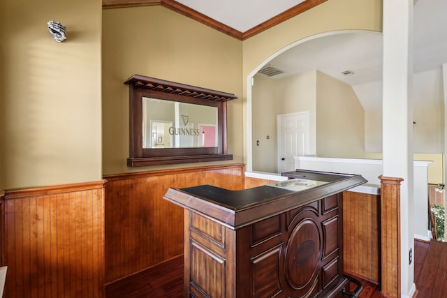 bar with dark wood-type flooring, lofted ceiling, and ornamental molding